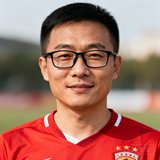 一位30岁左右的中国男性球迷头像，短发戴黑框眼镜，身穿红色足球T恤，背景模糊处理，表情真诚友善。
